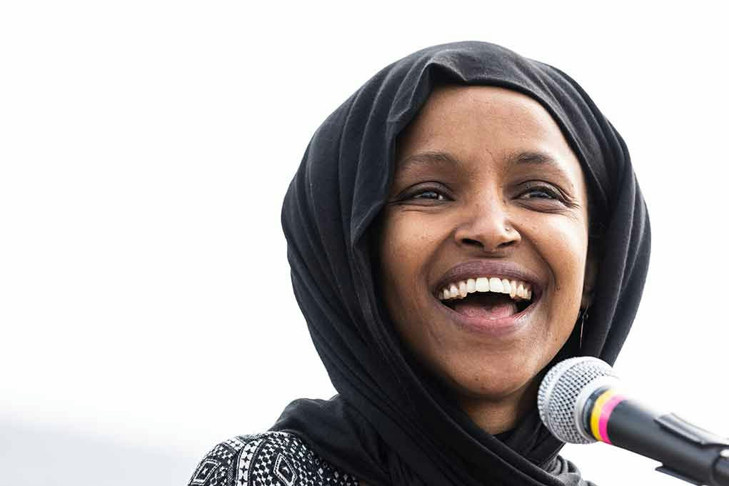 Smiling woman in hijab speaking into a microphone.