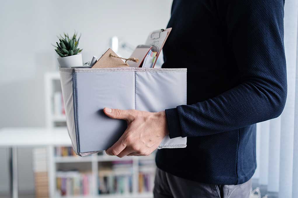 Person holding a box with office supplies.