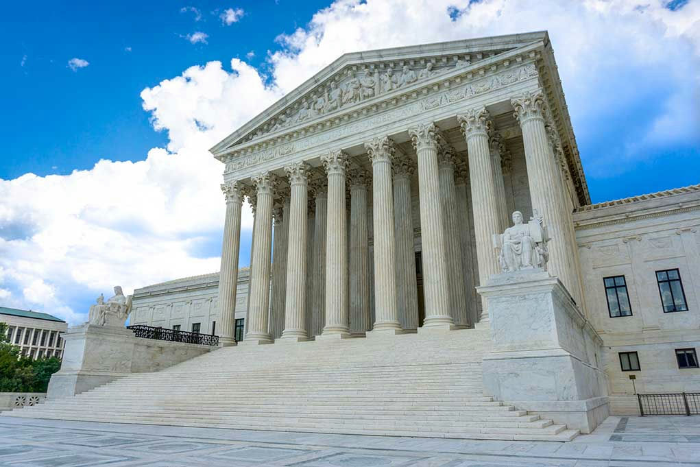 White building with columns under a blue sky.