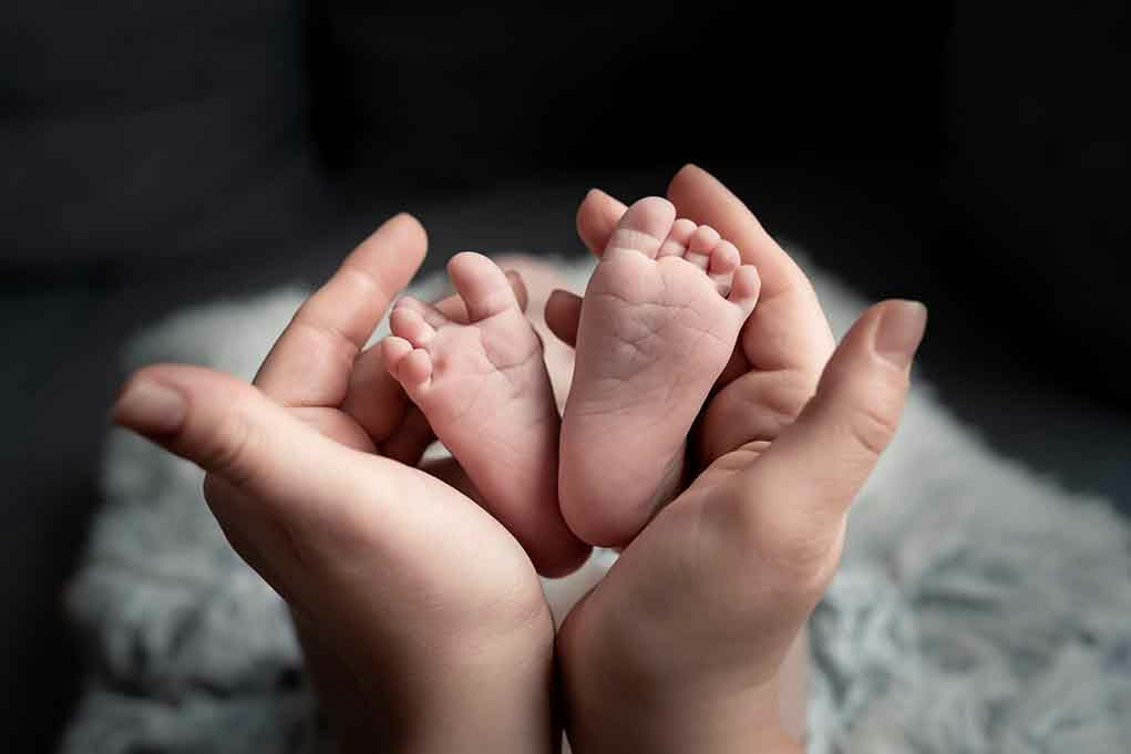 Hands holding newborn babys feet.
