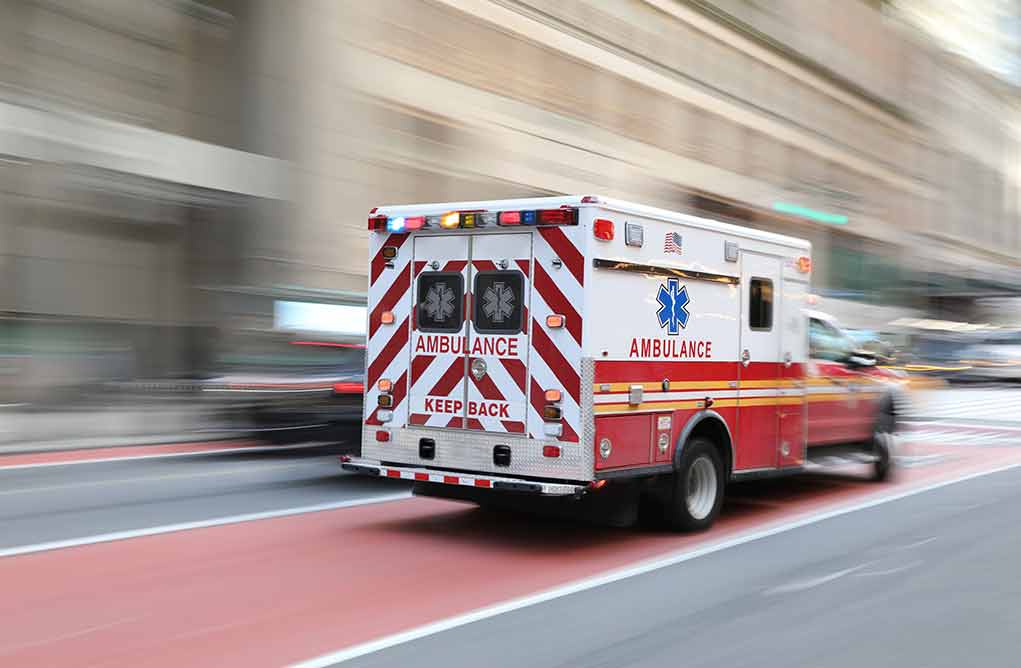 Ambulance driving on street with blurred background.