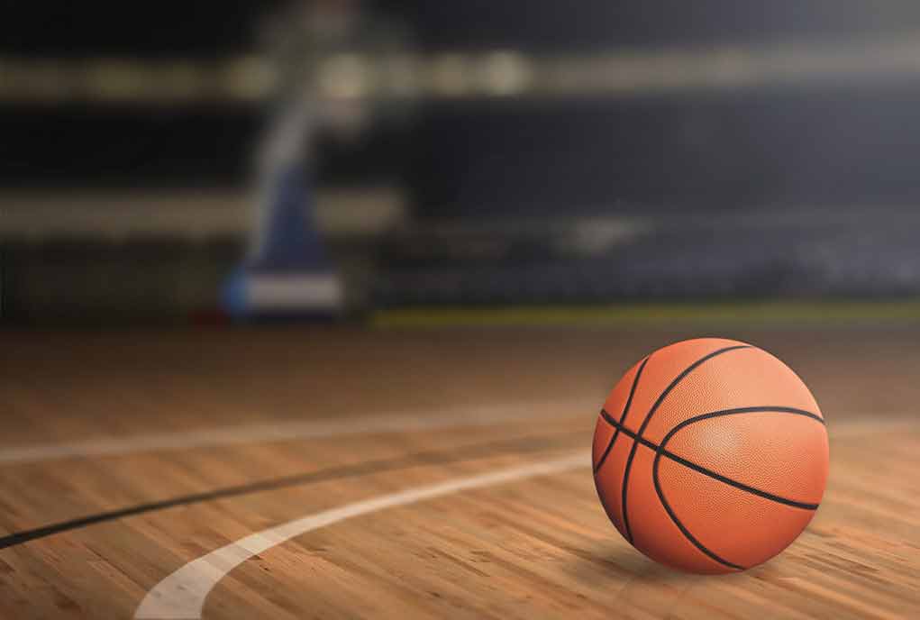 Basketball on an indoor court, hoop in background.