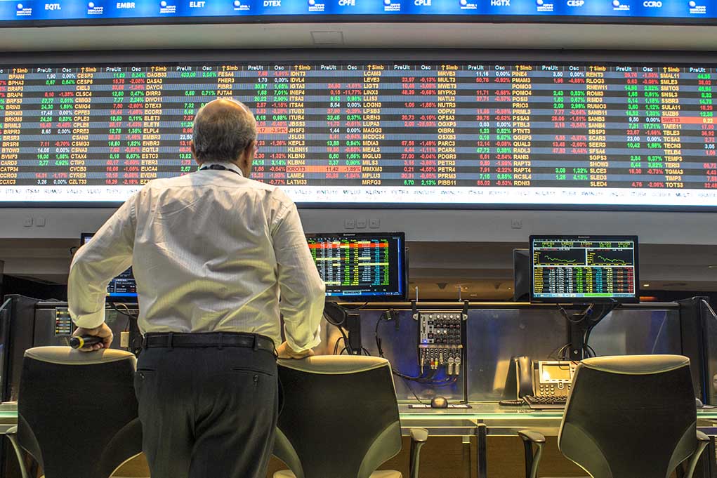 Person viewing stock market data on multiple screens.