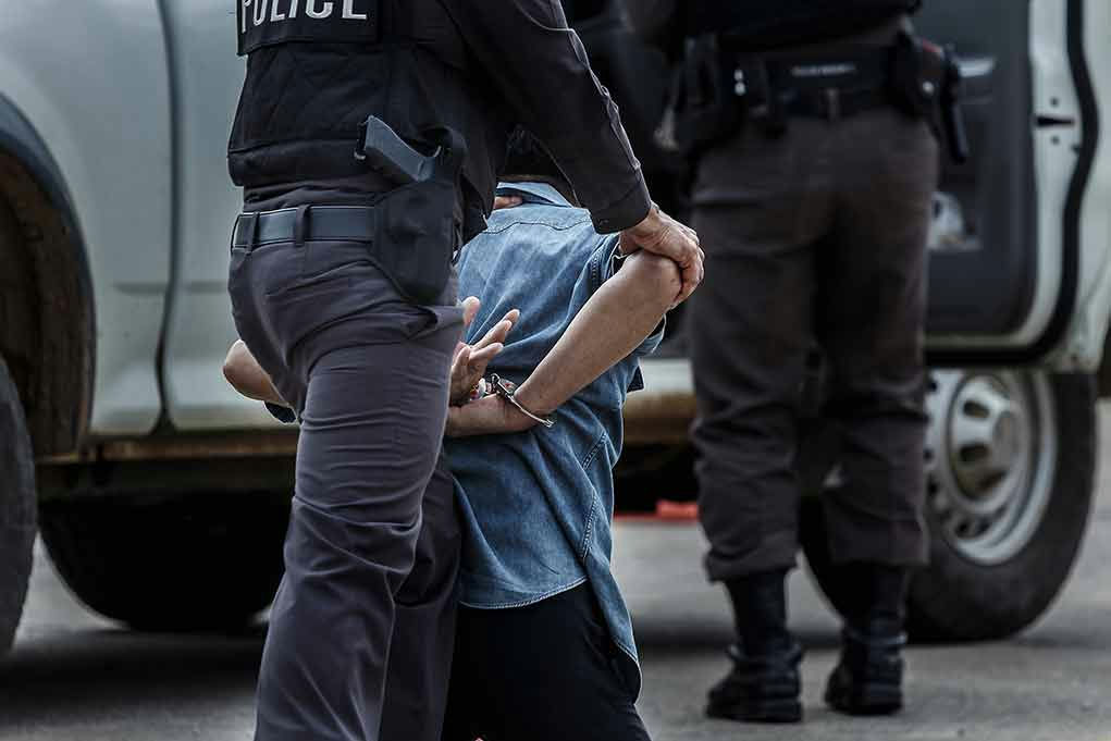 Police officer arresting and handcuffing a person.