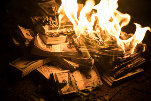 Burning stack of money in flames