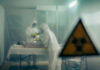 Two scientists examining a patient with biohazard sign visible.