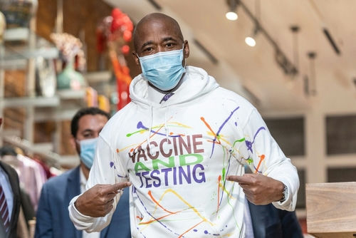 Man wearing Vaccine and Testing hoodie, pointing at text.