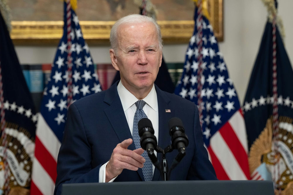 Man speaking at podium with American flags behind