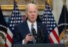Man speaking at podium with American flags behind
