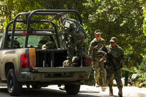 Soldiers loading equipment into a military vehicle in forest.