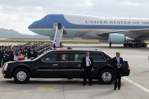 Presidential motorcade limousine in front of large government aircraft on tarmac