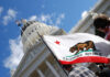 California state flag in front of Sacramento Capitol building.