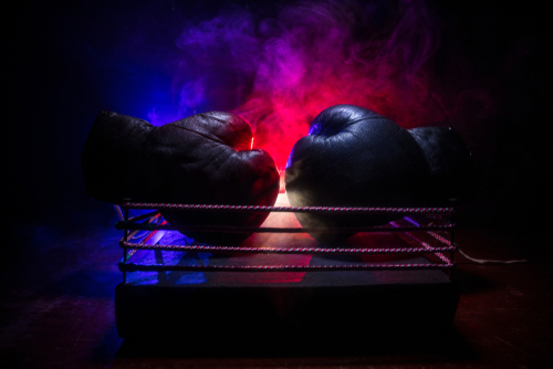 Two boxing gloves positioned in a ring with dramatic lighting and smoke