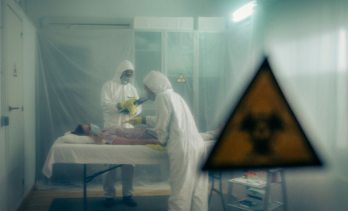 Medical personnel in protective gear attending to a patient in a hazardous environment