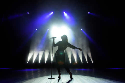 Silhouetted singer performing on stage with dramatic lighting.
