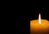 Lit candle in darkness.