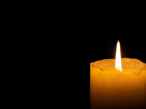 Lit candle in darkness.
