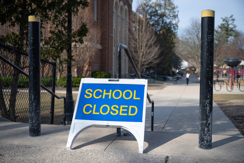 School closed sign on sidewalk near building.
