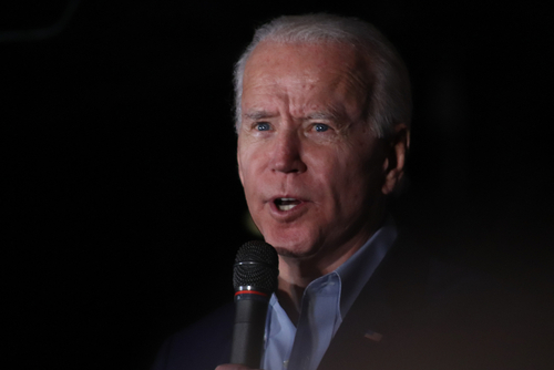 Man with silver hair speaking into a microphone.