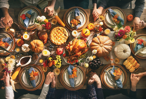 A beautifully arranged Thanksgiving dinner table with a turkey, pies, and autumn decorations