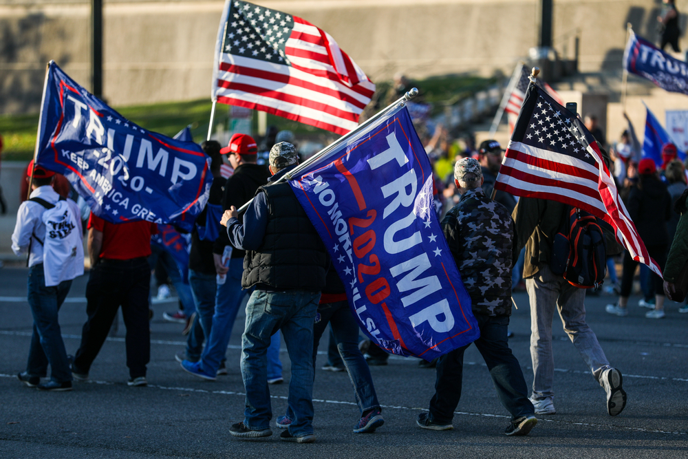 People holding Trump flags and American flags rallying