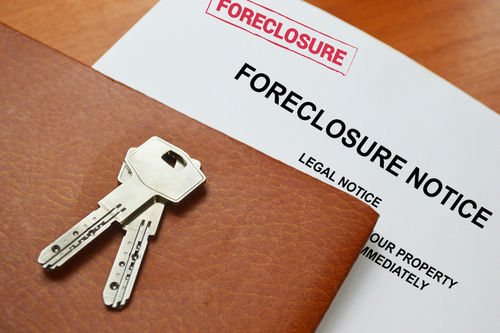 Keys on a foreclosure notice document and leather folder.
