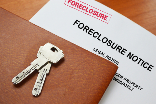 Keys on a foreclosure notice document and leather folder.