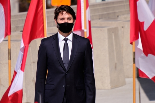 A man in a suit with Canadian flags in background.