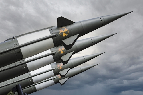 Four missiles with radiation symbols under cloudy sky.