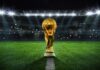 Golden trophy on soccer field under stadium lights