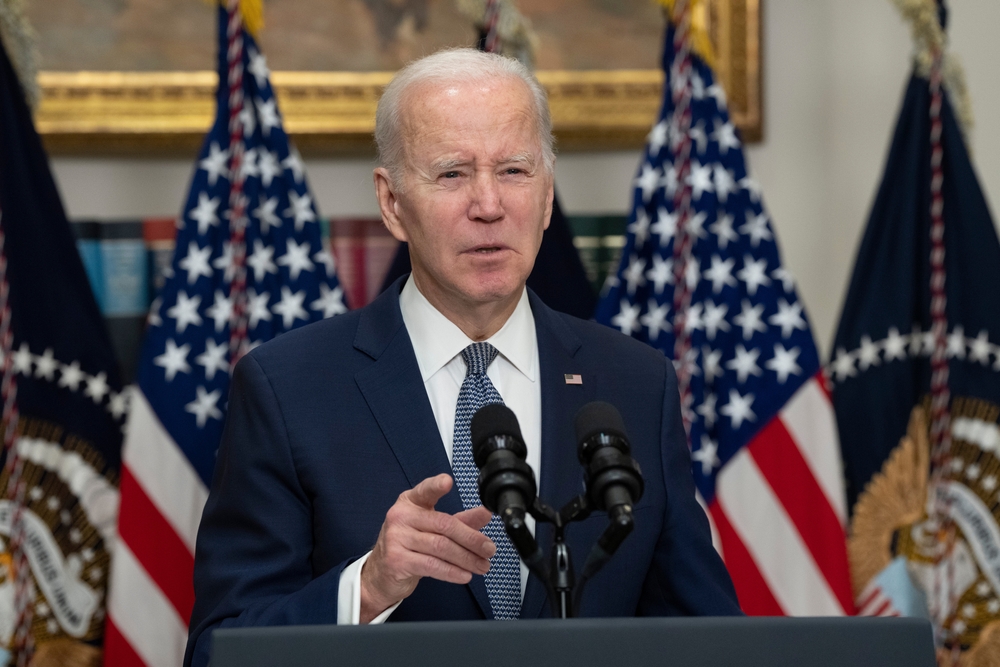 Man speaking at podium with American flags behind