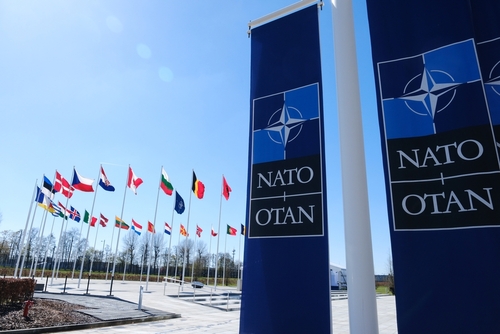 NATO flags displayed at the headquarters under a clear blue sky