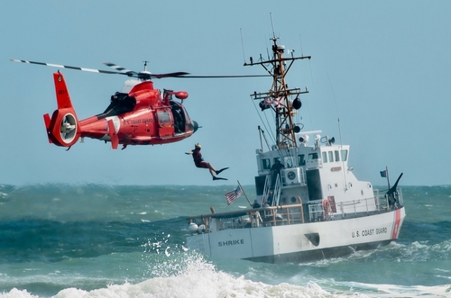 Coast Guard training with helicopter and boat in rough seas.