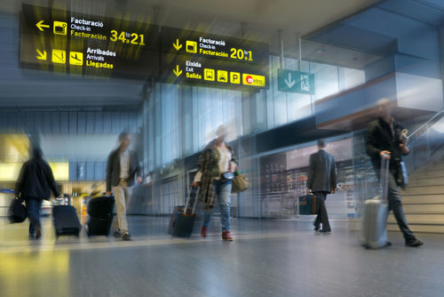 Travelers with rolling suitcases walk through an airport terminal