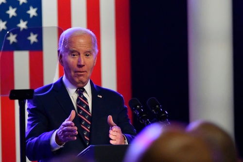 A man speaks at a podium with an American flag.