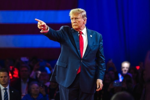 Man in suit pointing on a stage.