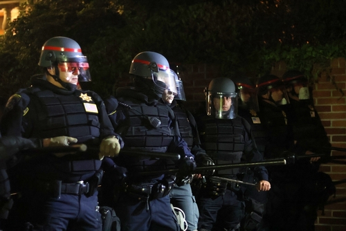 Police officers in riot gear standing in formation at night