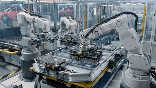 Robotic arms assembling components in a factory.