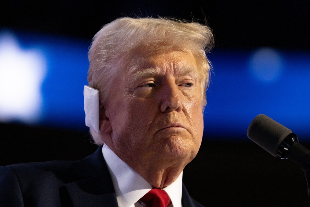 Donald Trump speaking at a microphone with ear device