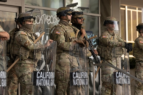 National Guard soldiers in tactical gear standing guard with shields