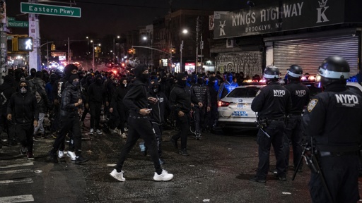 Crowd of people gathered on a street with police officers and vehicles