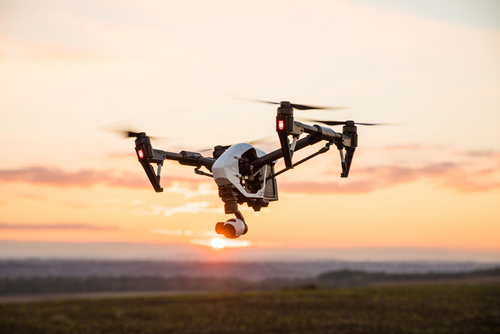 A drone flies at sunset over a field.
