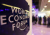 World Economic Forum sign with blurred people in background.