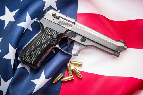 Handgun with bullets on American flag background.