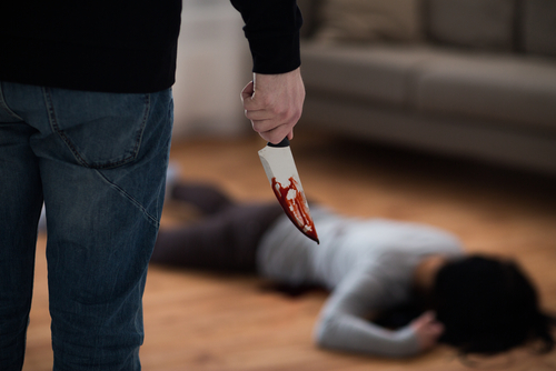 Person holding bloody knife with victim on the floor.