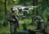 Soldiers in a forest operating a drone.
